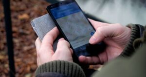 Pessoa segurando um smartphone Android aberto no aplicativo Google Maps, buscando um endereço