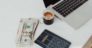 Mesa com calculadora, dinheiro e notebook durante planejamento de orçamento