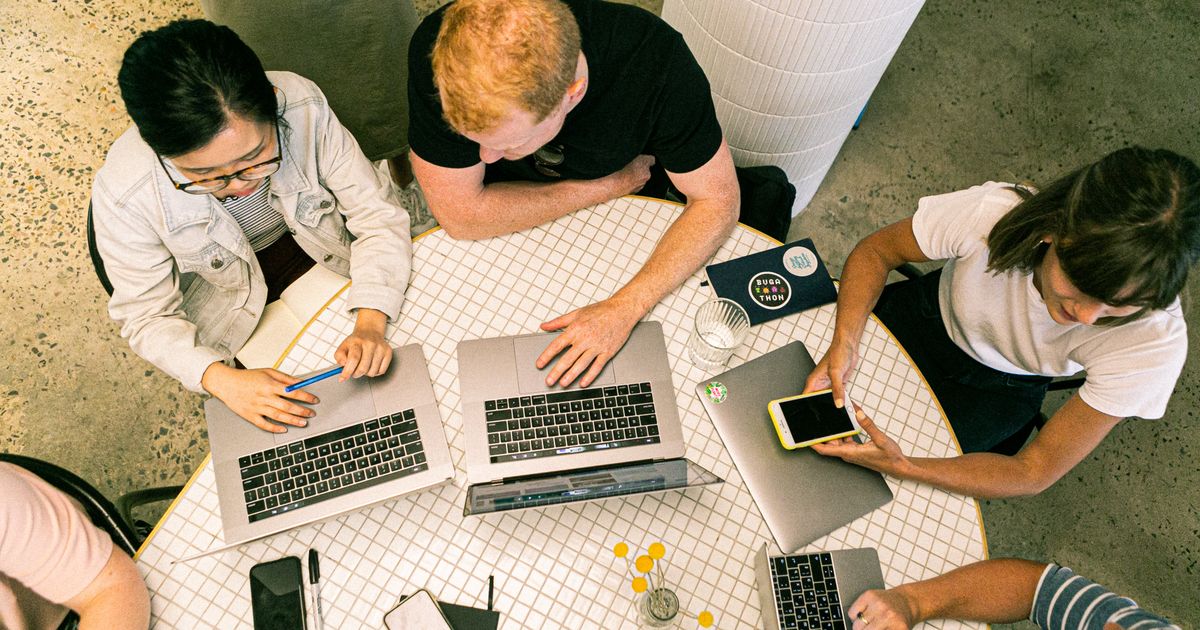 Vista de cima de equipe trabalhando com notebooks e celular em mesa de escritório