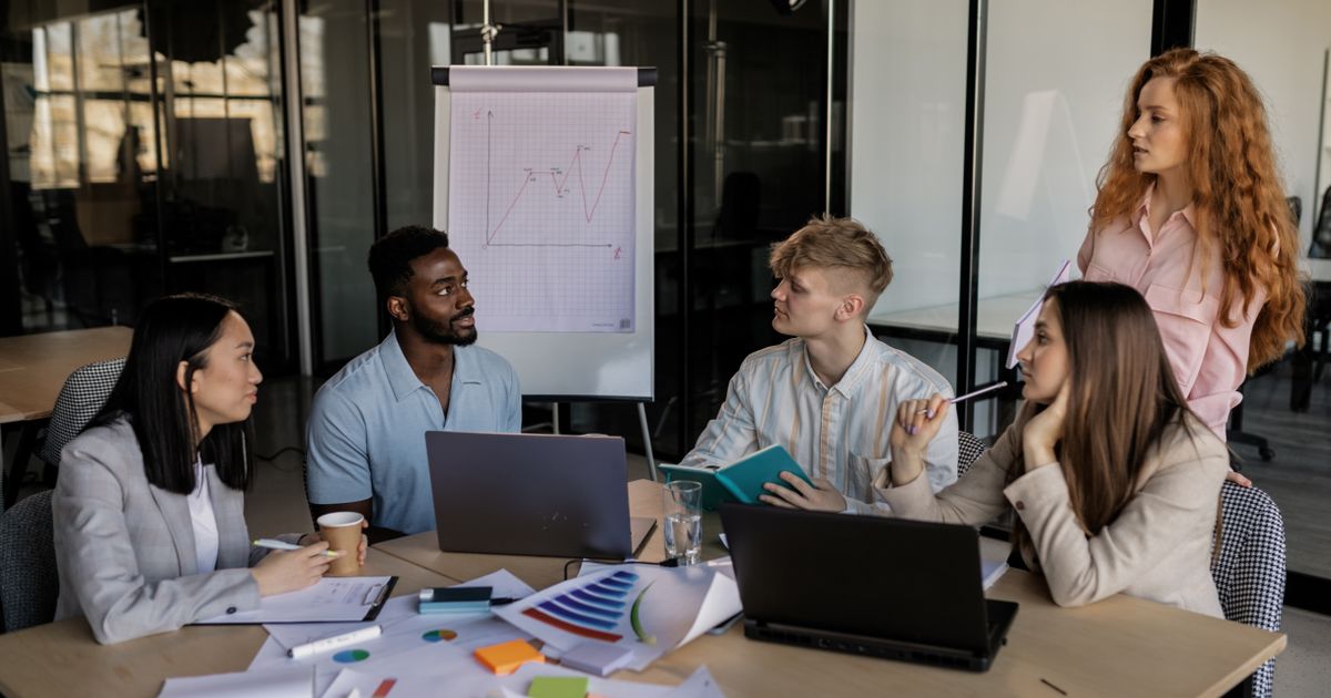 Reunião de equipe com notebooks e relatórios impressos sobre a mesa