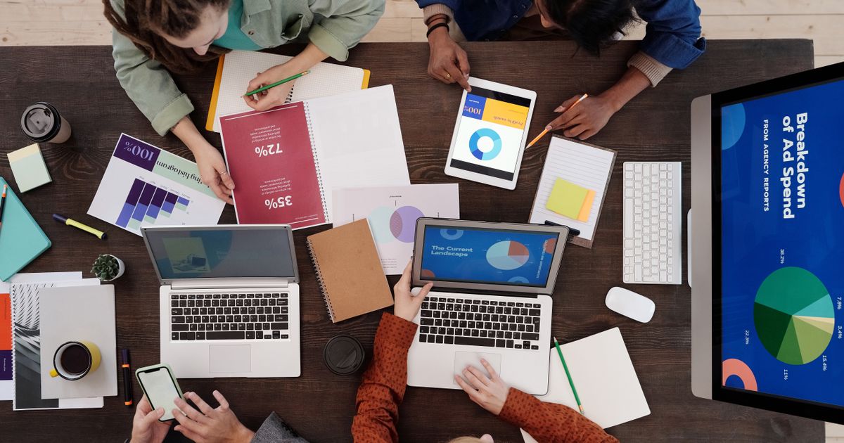 Equipe vista de cima usando notebooks e tablet com gráficos sobre a mesa