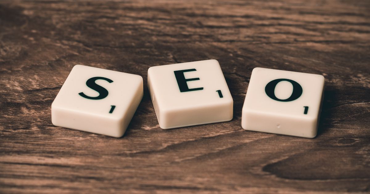 Peças de jogo de palavras formando a sigla SEO sobre mesa de madeira