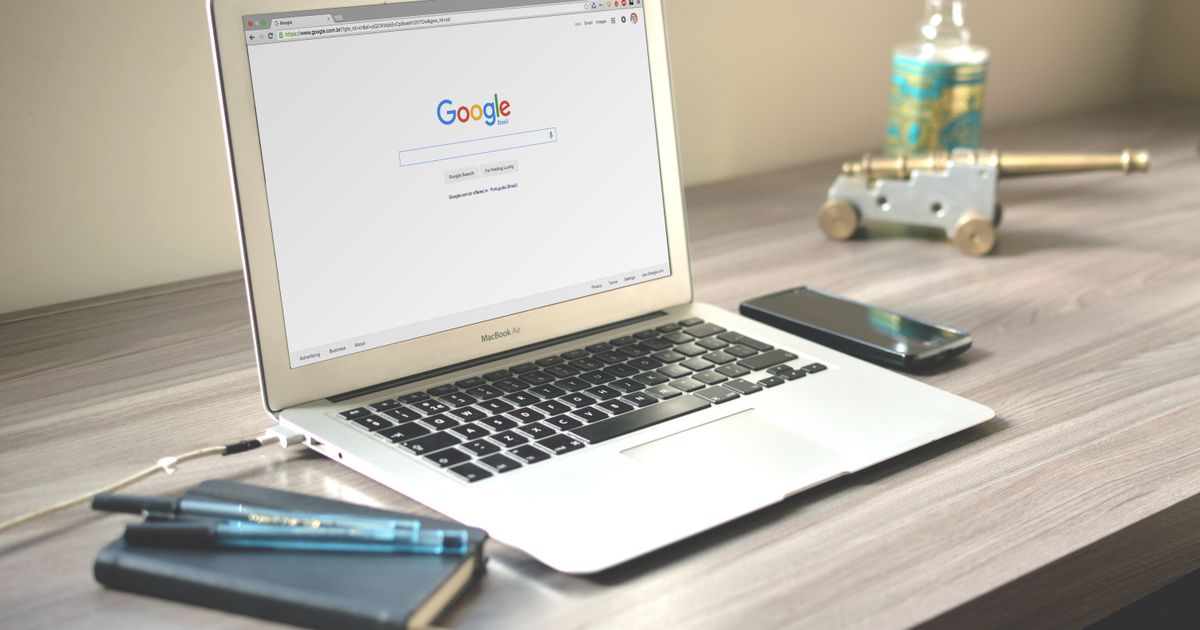 Notebook aberto na busca do Google sobre mesa de madeira, com celular ao lado