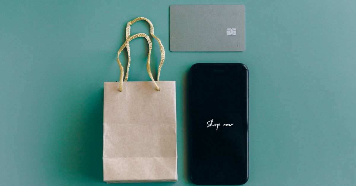 Celular com a mensagem Shop now ao lado de cartão e sacola de compras