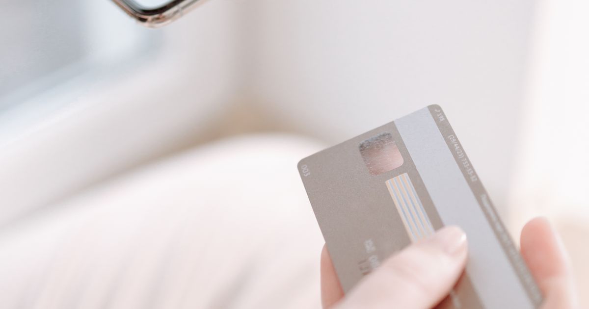Mãos segurando cartão diante do celular durante compra online