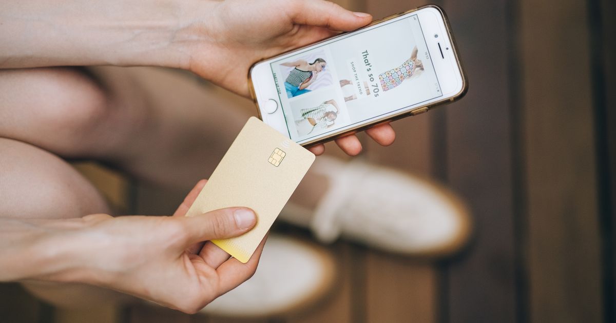Mãos segurando celular e cartão para finalizar uma compra online