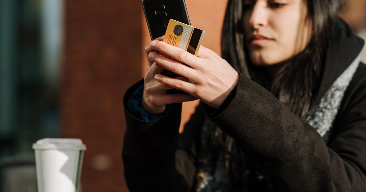 Jovem usando celular e cartão para concluir uma compra