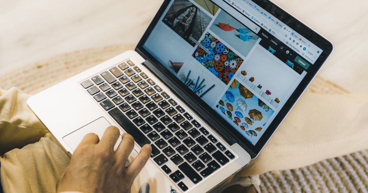 Mãos digitando em notebook com galeria de imagens de um site na tela