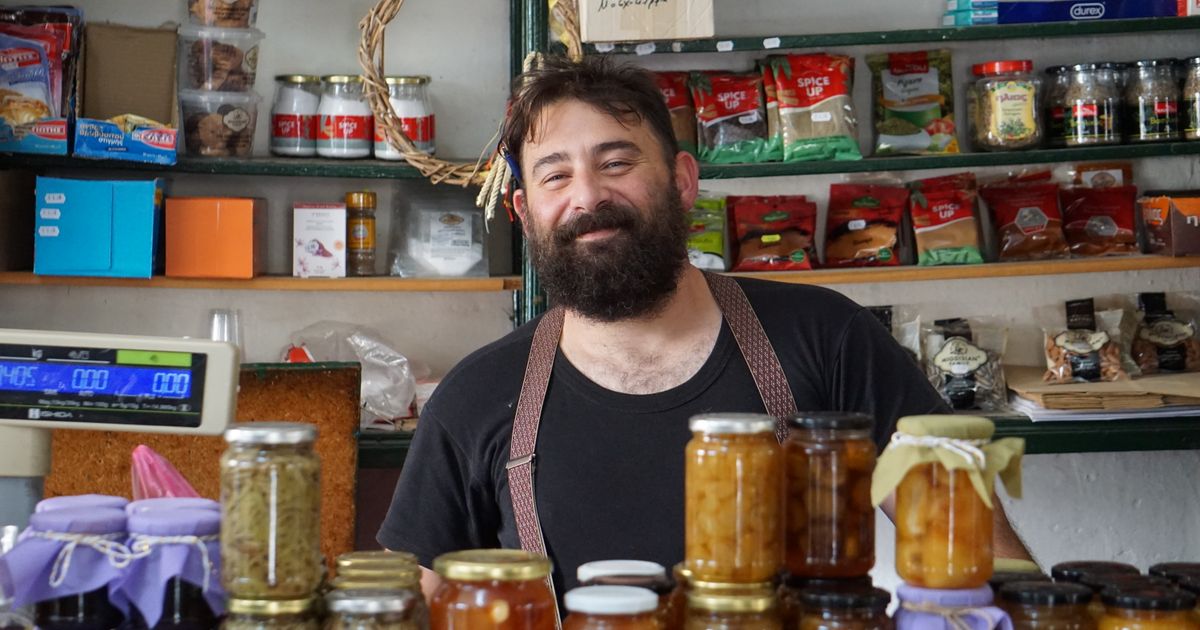 Comerciante sorridente atrás do balcão de uma loja de conservas artesanais